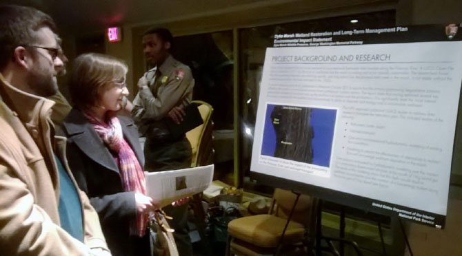 Ryan Stewart and Andrea Reese of the Northern Virginia Conservation Trust read a sign explaining the draft Dyke Marsh Restoration Plan and Long-Term Management Plan/ Environmental Impact Statement at a public meeting on Feb. 26