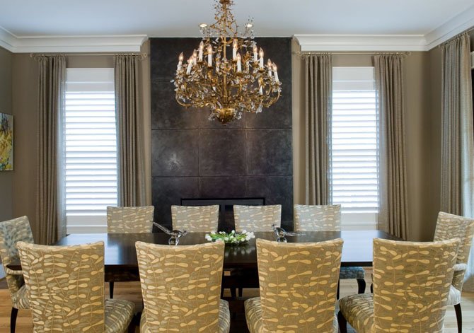 The large matte-finished tiles on the wall surround the fireplace in the dining room of this Bethesda home designed by Sharon Kleinman is upscale but informal.