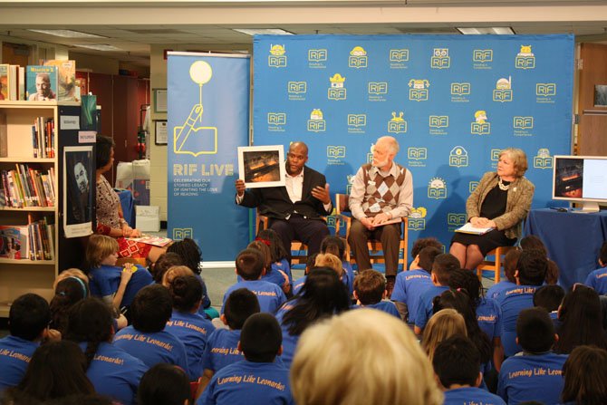 Third grade students at Barcroft Elementary and Dr. Judy Cheatham, vice president, Literacy Services at Reading Is Fundamental (right), listen to author Steven Sellers Lapham (center) and illustrator R. Gregory Christie (left), read from their new children’s book, “Philip Reid Saves the Statue of Freedom.”