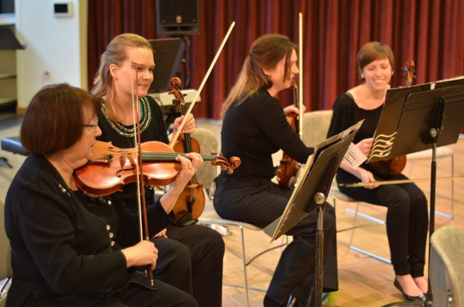 The Reston Community Orchestra is composed of musicians from throughout the northern Virginia area. From left, Bonnie Hudson, Sarah Connelly, Emily Hufnagle, and Erin Lindgren prepare their violins for a concert at Reston Community Center.