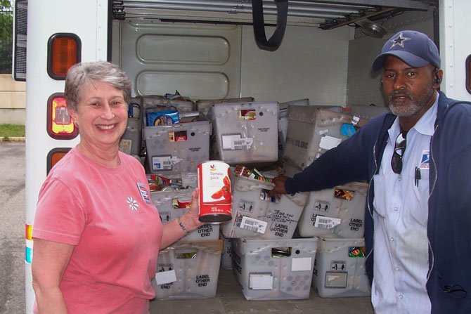 Parkfairfax Letter carrier Dwayne Chittum, right, is joined by Beth Campbell of ALIVE! during last year's Stamp Out Hunger food drive. This year's food drive collection will take place on Saturday, May 10.
