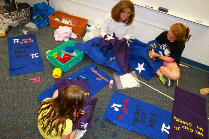 Left to right, top to bottom, parent Amy Augenblick works with fifth grade student Elizabeth Augenblick and fourth grade student Sophia Fox to create banners for Rocket Days.