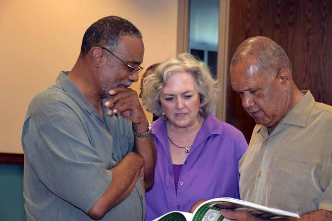 At a reception at Wakefield on May 22, Clayton Powell, Conchita Mitchell and Larry Randall look at "Integration of Wakefield Highs School" that Mitchell co-authored.