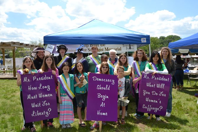 Pictured in the group photo of Troop 707 and women dressed as suffragists are, from left:  Back row: (Suffragists) Julianne Smith, Sue MacIntyre, Lynne Dudurich, (scout leader) Karan Wright, Savannah Dingle, Sally Miller, Kathryn Wingard, Grace Strong, Maryn Ballard, and (scout leader) Erika Malos-Keil.  Front row: Annette Wright, Alexandria Strong, Lily Miller, Kiera Gilbert, Ellen Keil, and Henry Keil.