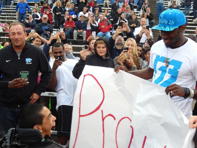 Juwaan sees RGIII for the first time, while Centreville varsity football coach Chris Haddock (on left) looks on and people photograph Juwaan’s reaction.
