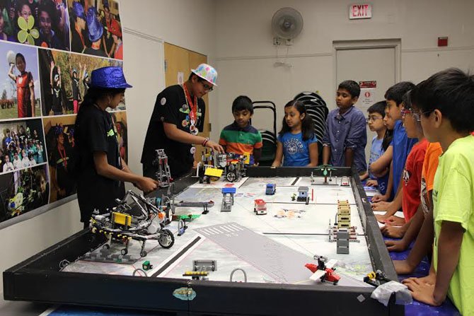 Mentoring at the Reston Library, Team Positive Aftermath teaches the logistics of building a lego robot structure.