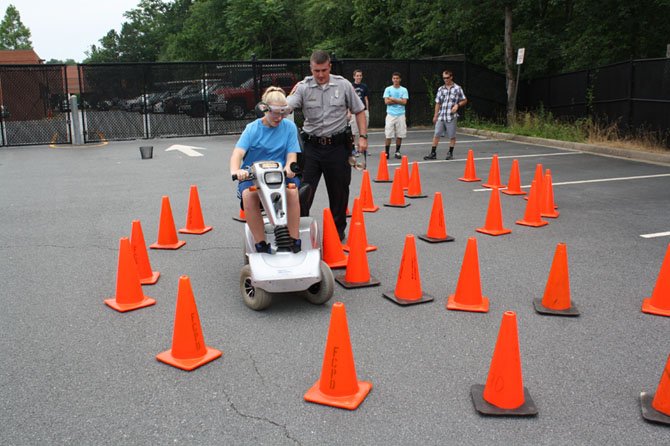 Madison Randles with Officer Patrick Nolan of the Fairfax County Police Department use a DUI Convincer at last summer’s program to show how consuming alcoholic beverages impairs judgment when operating a motor vehicle.