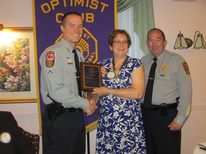 Fairfax County police officer PFC Philip C. Stone [left] accepts the “Charles A. Robinson Jr. Respect for the Law” award from Vienna Optimists’ vice president Michele Wright. Captain John Naylor, Commander of the Fair Oaks District Station, introduced Stone.