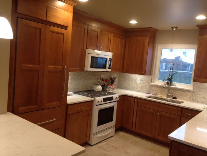 Designer Sherry Wohn removed a bearing wall between the bungalow's kitchen and the dining room, replacing it with a two-seat dining counter surfaced in an off-white quartz composite that also doubles as a serving station. Maple wood Shaker-style cabinet facings give the kitchen — which can now be seen from the living room — a relaxed, cohesive look.
