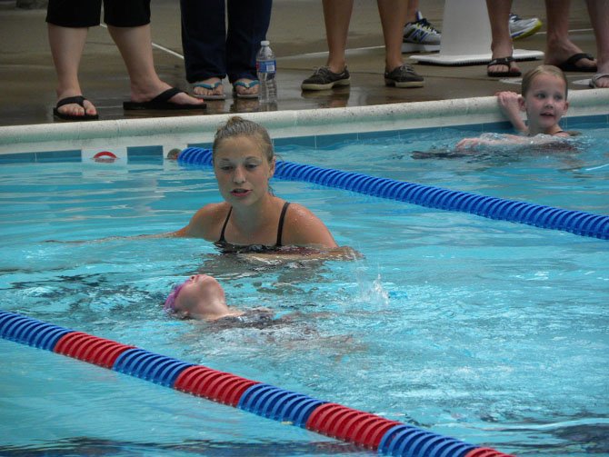 Coach Wesley Kittelberger, 16, guides a swimmer during the 8 and under competition, at the Burke Centre Swim Club on Wednesday, July 9.