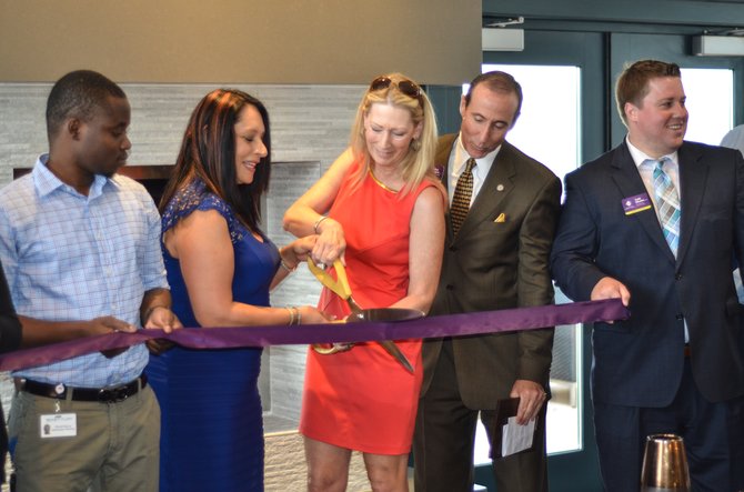 Katherine Cordero, property manager for Metropolitan at Reston cuts the ribbon with Reston Chamber of Commerce Board Chair Karen Cleveland on the rooftop of the Metropolitan at Reston.