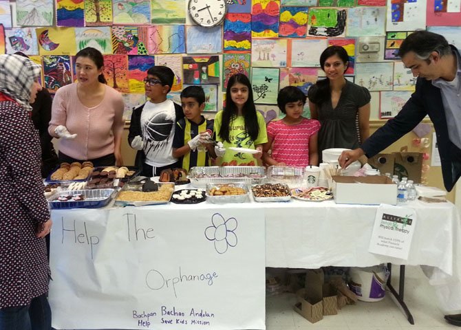 Wearing yellow shirts, Kushaan and Medhnaa Saran work at the bake sale with their friends.