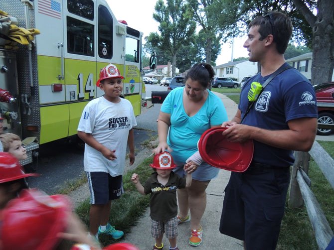 Firefighter Happ Radam of Engine 14 in Burke talks with Jack Sejas, 11, about fire safety. Radam handed out hats to all the kids before they climbed into the engine to discover what was inside.
