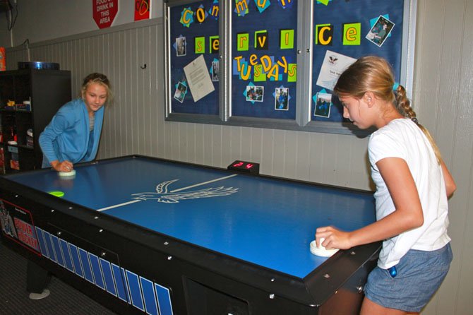 From left, Erin Schlegel, 12, and Sophie Tedesco, 12, play air hockey at McLean Teen Center’s Back-to-School night.