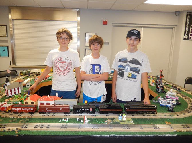 (From left) are Zach Pavis, Cadence Hinnant and Jackson Van Ness with the train layout they built together.
