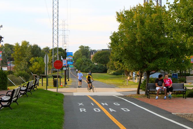 A cyclist and pedestrian cross a street on the Washington and Old Dominion Trail.