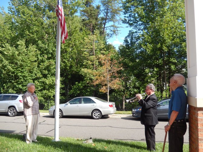 Theodore Smith plays “Taps” while (from left) Charlie Schuck places his hand over his heart and Jack Barbee salutes.