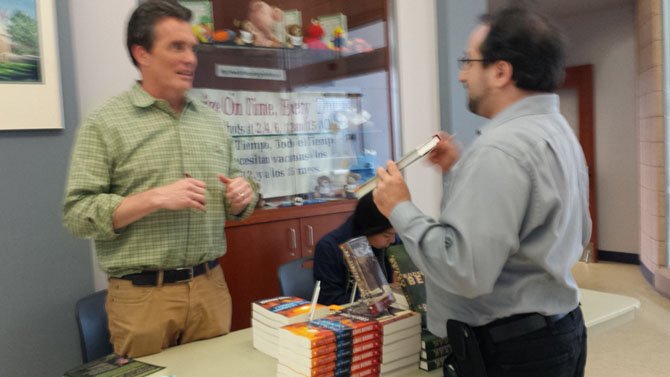 Author Louis Bayard (left) signs a copy of a book for a fan. 