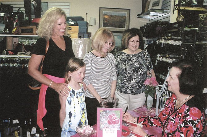 Sharon Allen Gilder (seated) autographs her new novel, “The Rose Beyond” last week at The Surrey. Waiting for their autographed copies are (from left) Beth Garagusi with daughter, Charlotte; Ellen Gordon and JoEllen Brayer.