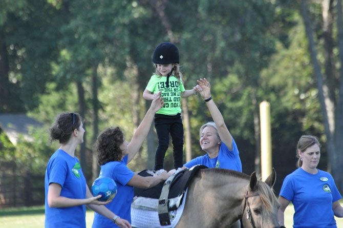 (From left) NVTRP volunteers Katie Breese, Debbie Heitmann, Patti Towsley and Sarah Maceyak supervise Alyssa Peterson (center) during a therapeutic riding demonstration.