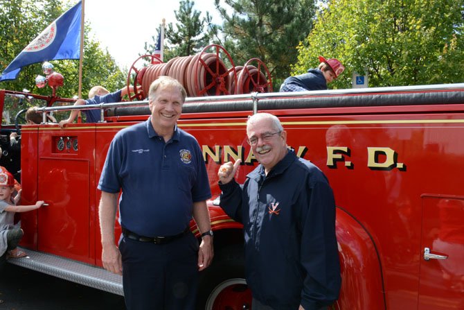 Howard Springsteen (left) of the Vienna Town Council and U.S. Rep. Gerry Connolly (right) hand out plastic fire helmets in front of a 1946 fire truck at the Oct. 4 Oktoberfest in Vienna.
