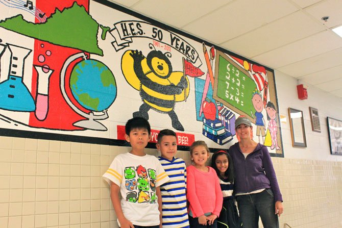 Herndon Elementary fourth grade students Gia Nguyen, Christian Abarca, Tea Geary and Nandana Rajesh with PTA President Amanda Geary in the school hallway. The PTA’s new sponsorship program puts less pressure on parents to donate money to the school.
