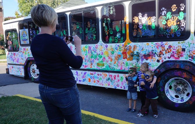 Lucas Abarca, 4, Aurora Hershman, 5, and Reid Hershman, 5, pose for a photo Oct. 4 after adding their handprints to the DASH bus art project as part of Art on the Avenue.