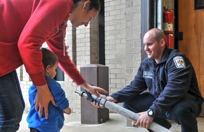Firefighter/paramedic Christopher Adkins demonstrates the use of a fire house to his nephew Timmy and Timmy’s mother Crystal Adkins at the Mount Vernon Station on Sherwood Hall Lane.
