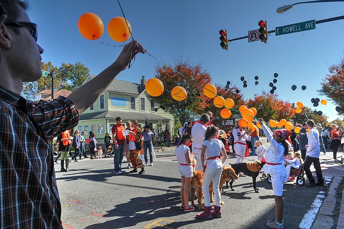 Volunteers add a long string of seasonally colored balloons to the start line of the Halloween parade.