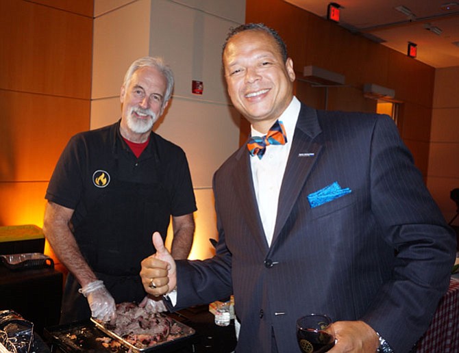 ”Mango” Mike Anderson, left, dishes out Sweet Fire Donna’s BBQ to Burke and Herbert vice president Walter Clarke at the Rotary Club of Alexandria’s Taste For Giving fundraiser Oct. 24 at the USPTO.