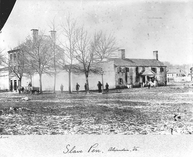 Civil War-era photo of Franklin and Armfield Slave Pen. Showing the original 1812 main building (on left, three-stories with the two chimneys), the probable kitchen and tailor shop (low building on right with two chimneys), and some sort of roofed area of unknown use behind the white-washed wall.