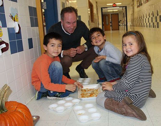 Churchill Road first graders Elliot Pomper, Selim Chareib and Katie Krokowski practice counting in tens by sorting 10 pumpkin seeds in each muffin tin, while their teacher, David Suchoski, looks on.
 