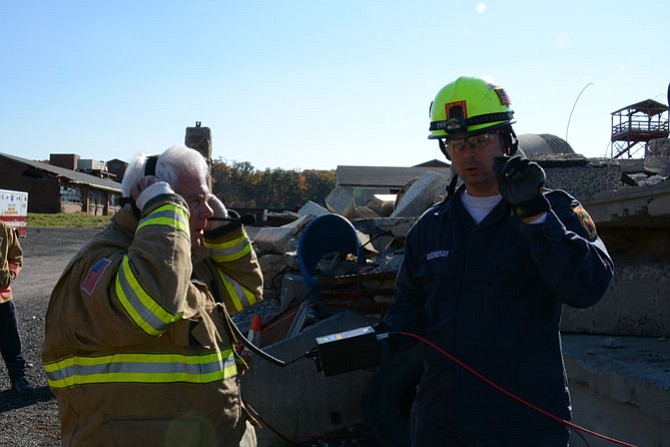 Technician Rob Schoenberger helps Terrance Moran listen for distress knocking using the Delsar seismic sensor device.
