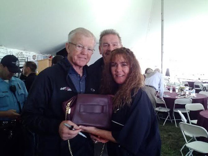 (From left) Former Redskins head coach Joe Gibbs, Redskin Ron Saul and Saul’s wife Robin Robison raise awareness for domestic violence with the Kerry Washington-designed purple purse.
