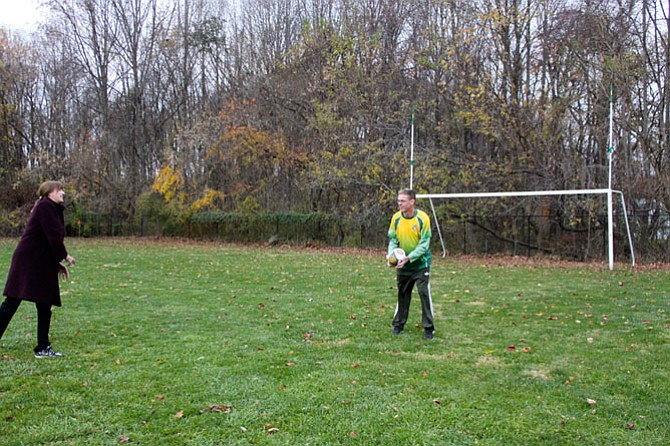 Theresa and Gary Coetzee toss a rugby ball in the field behind Great Falls Library.
