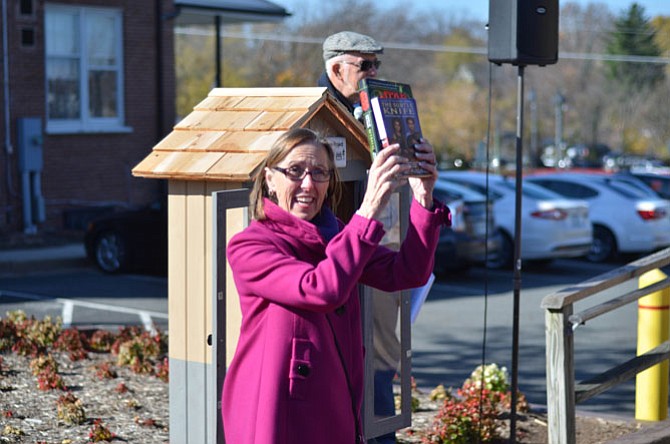 Herndon resident Mercia Hobson, a member of the Herndon Rotary Club, displays some books available at Herndon’s first Little Free Library on Saturday, Nov. 15. There are three shelves for donated books in the weatherproof box for books.