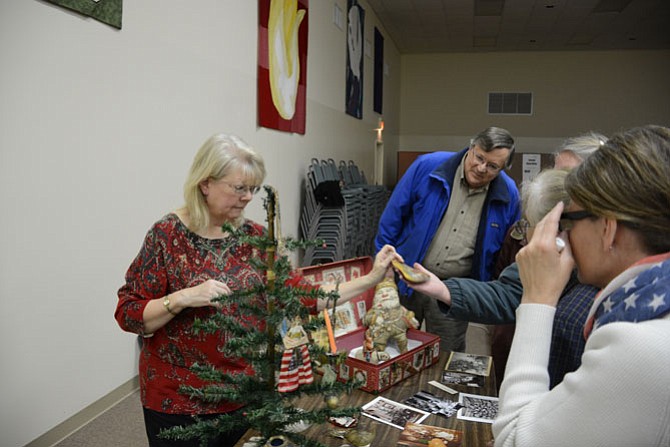 Linda Lau of Fairfax (left) shows off her collection of Victorian Christmas decorations and toys for Mike Deloose of West Springfield (center) and others at the Nov. 23 meeting of the Burke Historical Society.
