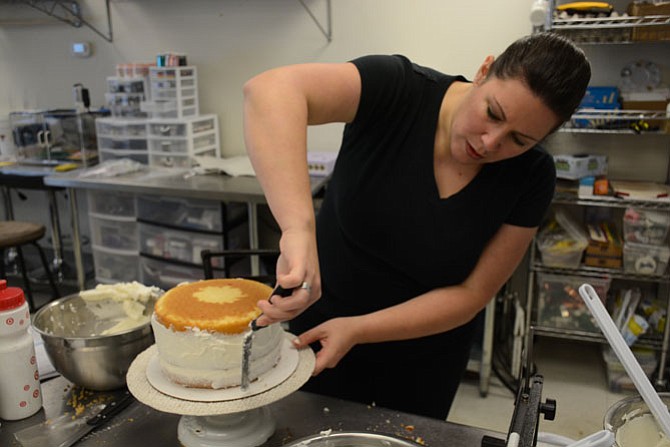 Occasionally Cake owner and cake designer Sabrina Campbell ices a layered vanilla cake with “Classic Vanilla” frosting.