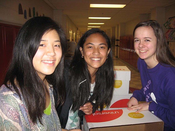 From left, seniors Meghan Chen, Bao Randrianarivelo, and junior Mariella Toro, wrap and reinforce boxes that will contain food and supplies for students at Marshall Road Elementary School in Vienna.