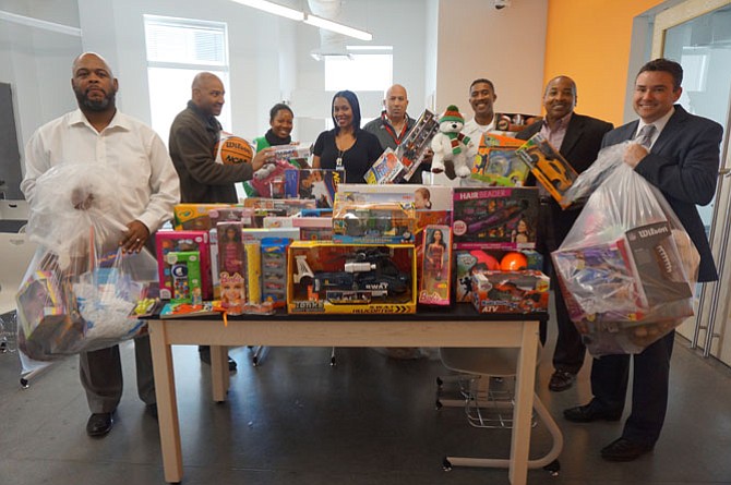 Jefferson-Houston Elementary School principal Chris Phillips, right, accepts toys donated to his students by members of the Departmental Progressive Club on Dec. 15. Pictured with him are Sherman Deck, Norman Reynolds, school social workers Karima Wade and Arnecia Moody, Willie Bailey and Merrick Malone.
