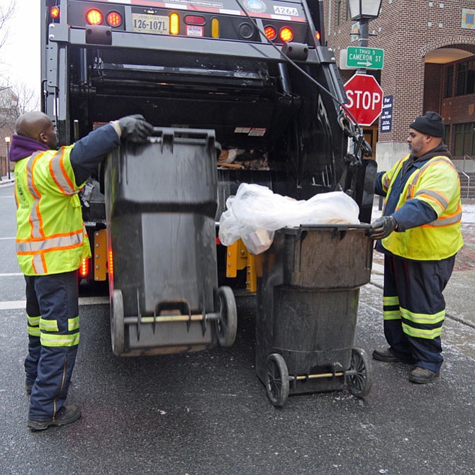 Vince Green (right) and his partner Anthony Jones ready two large garbage cans for dumping in the back of refuse truck #4266. 
