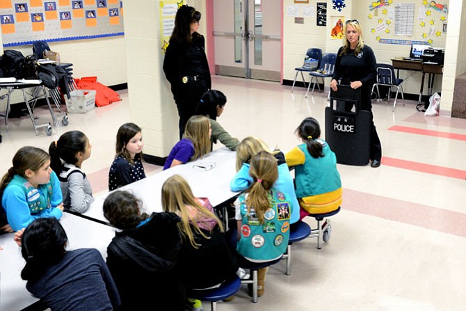 Team Leader Jeanne Graupmann and Postal Inspector Heidi Lescault talk about law enforcement responsibilities with Girl Scouts of Troop 6080 on Monday, Jan. 12 at the Crossfield Elementary School in Herndon. 