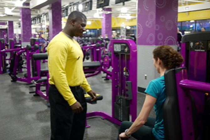 Trainer Manny Danso works with a client at Planet FItness