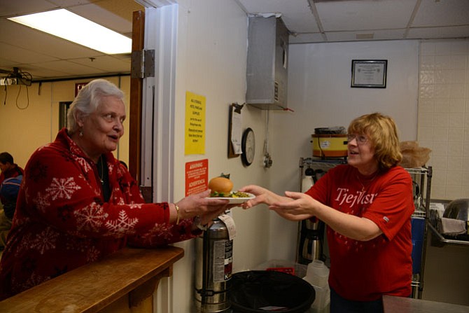 Mount Vernon residents and members of Aldersgate United Methodist Church Karen Latta (left) and Gunnel Hamilton (right) pass plates of food to be served to overnight guests of Rising Hope Mission Church.