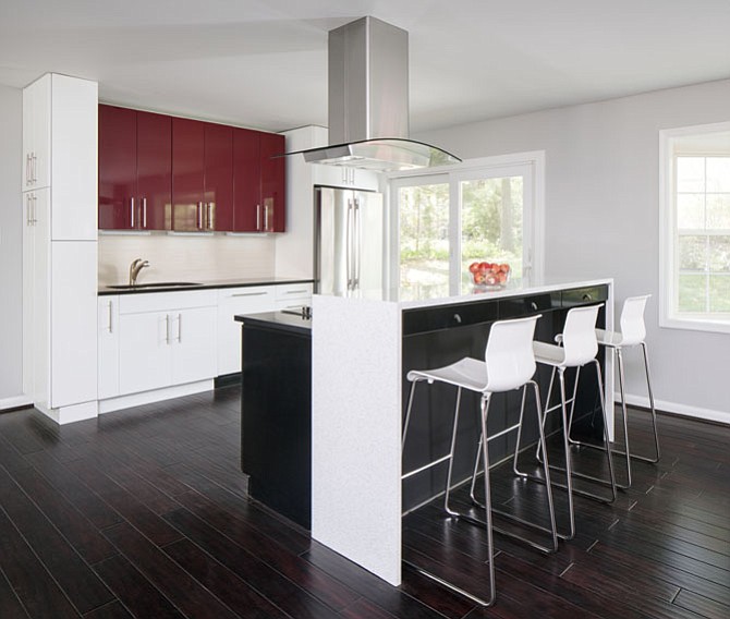 This ultra-modern kitchen, designed by Nicely Done Kitchens in Springfield, features red, white and black cabinetry and a muted gray backsplash.