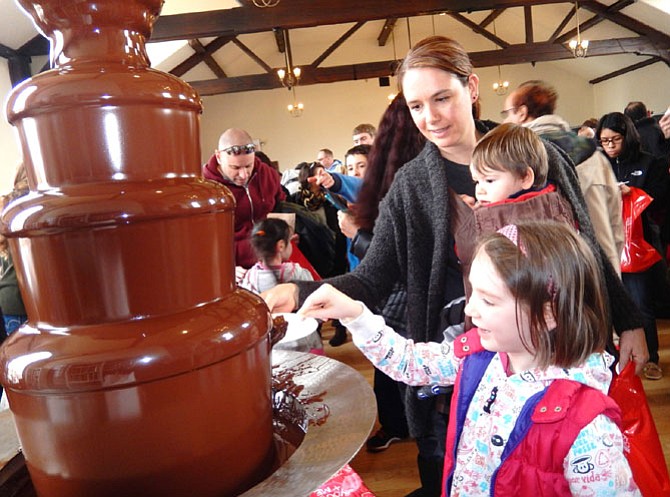 Lily Mae Hamilton, 5, happily dips a treat into the chocolate fountain while mom Lora Ann and brother Jack, 1, watch.

