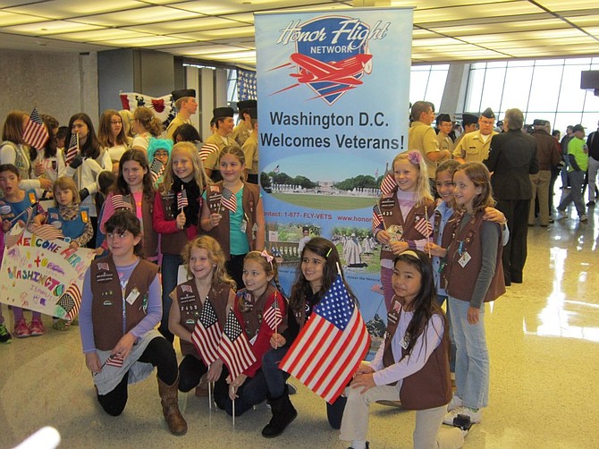 Members of Girls Scout Troop 3651 greeted an arriving Honor Flight at Dulles International Airport when they were Brownies in 2012. They are organizing a showing on “Honor Flight” on March 16 in Herndon to bring more veterans to Washington.