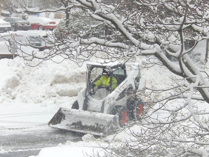 This Bobcat driver clears the snow from a residential road.