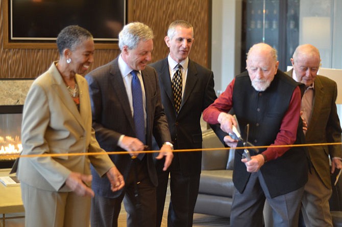 Reston founder Bob Simon holding the scissors for the Saturday, March 14 ribbon cutting for the Harrison Apartments by Reston Parkway in Reston. Also in the picture are Supervisor Catherine M. Hudgins (D-Hunter Mill), Renaissance Centro managing members Albert H. “Sonny” Small and Douglas Erdman, and Albert H. Small.
