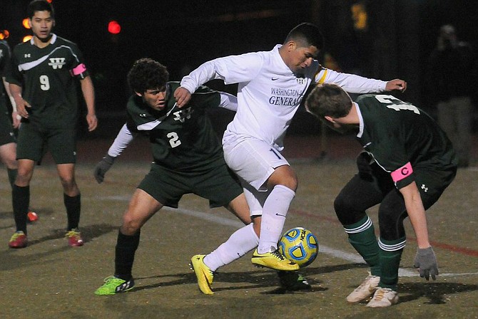 Washington-­Lee forward Maycol Nunez tries to split a pair of Wakefield defenders on March 27.